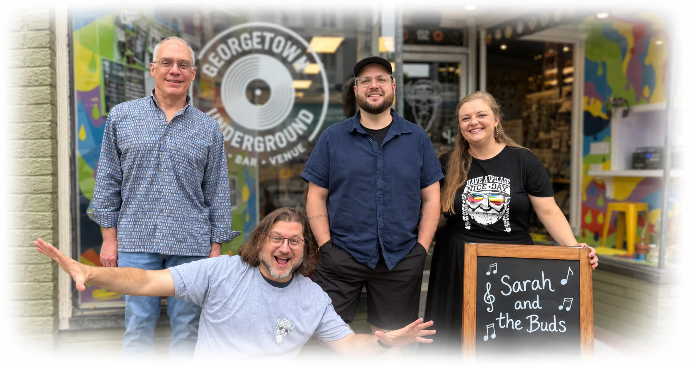 Sarah & the Buds outside Georgetown Underground, a record shop and venue, with a chalkboard sign reading Sarah and the Buds.